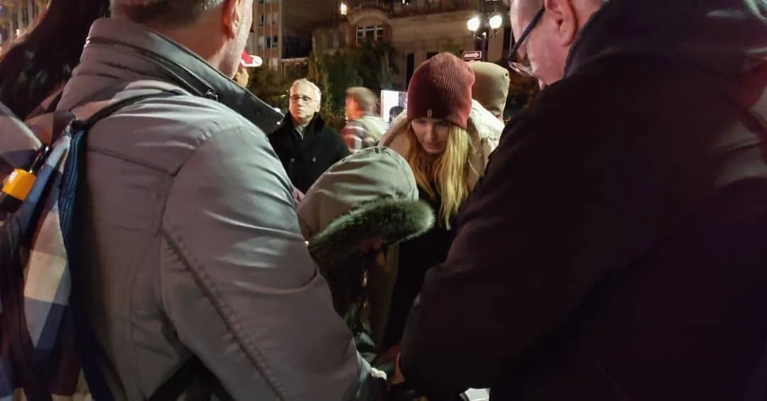 Believers gathered close around someone to pray at night downtown
